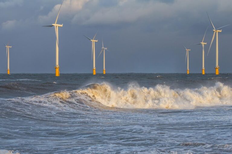 Offshore wind turbines with waves in the foreground.